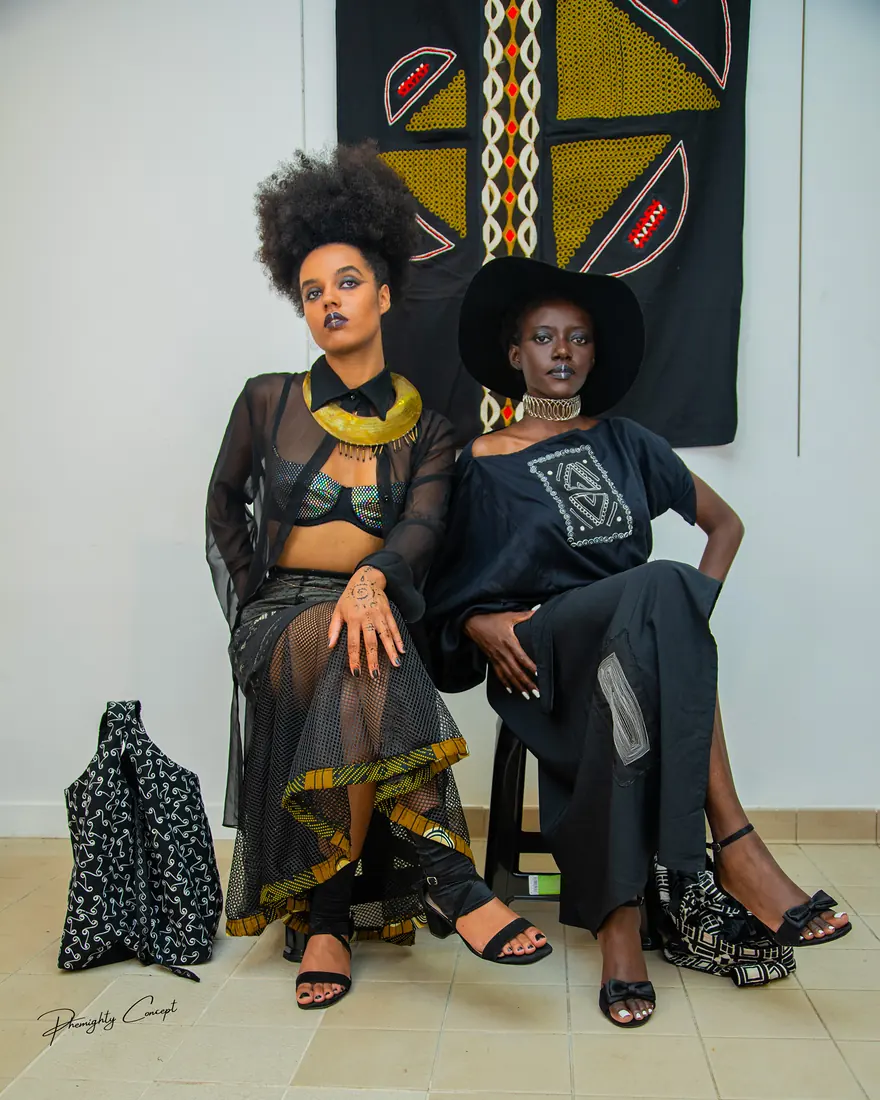 Deux mannequins assis devant une tenture en wax
